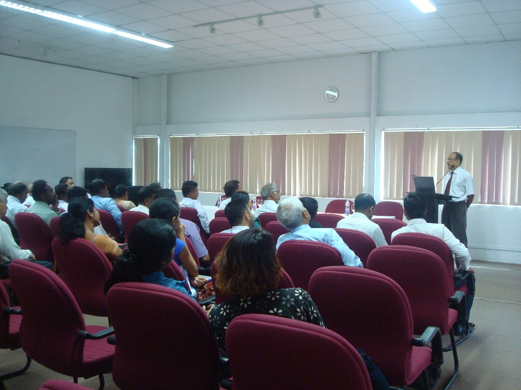 a lecture room full of people in red chairs