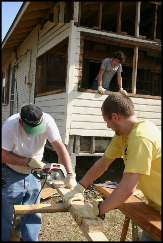 two men working on the back of a house