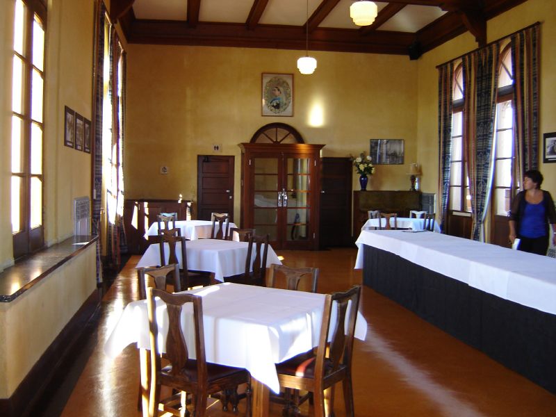 empty tables with white tablecloths are lined up in the dining room