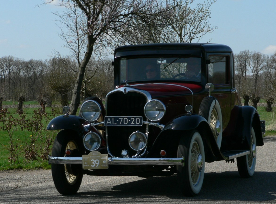 an old model car with a man standing behind it