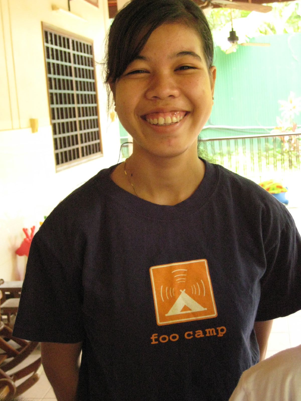 a young man with a black shirt smiles while standing next to a window