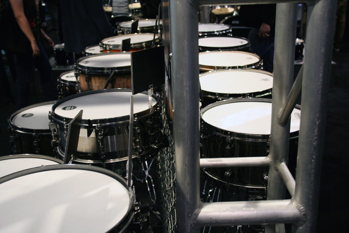 a row of drum heads are positioned by a metal fence