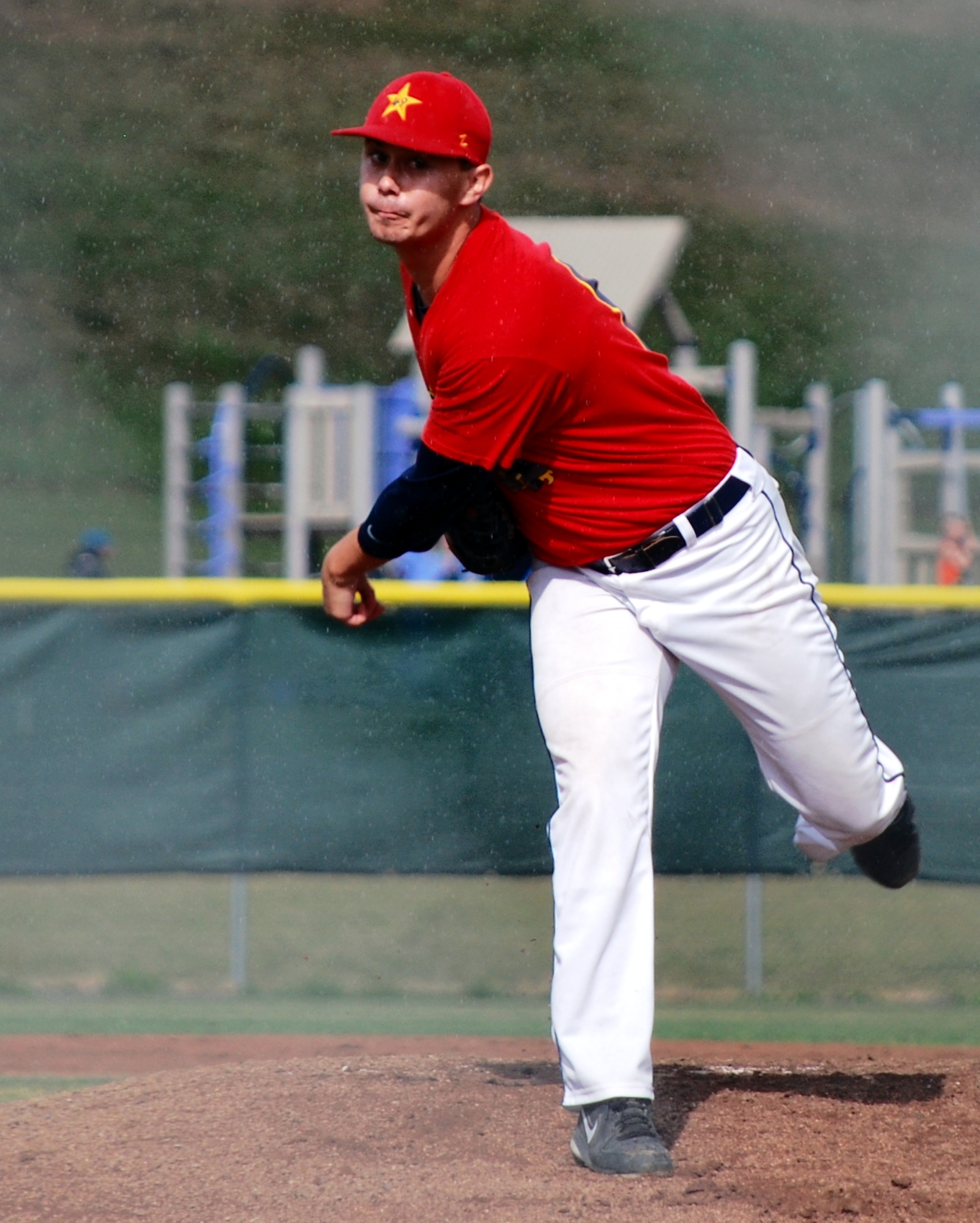 baseball pitcher standing on mound with hand out in motion