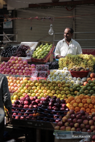 a man standing at a fruit stand surrounded by baskets of fruit