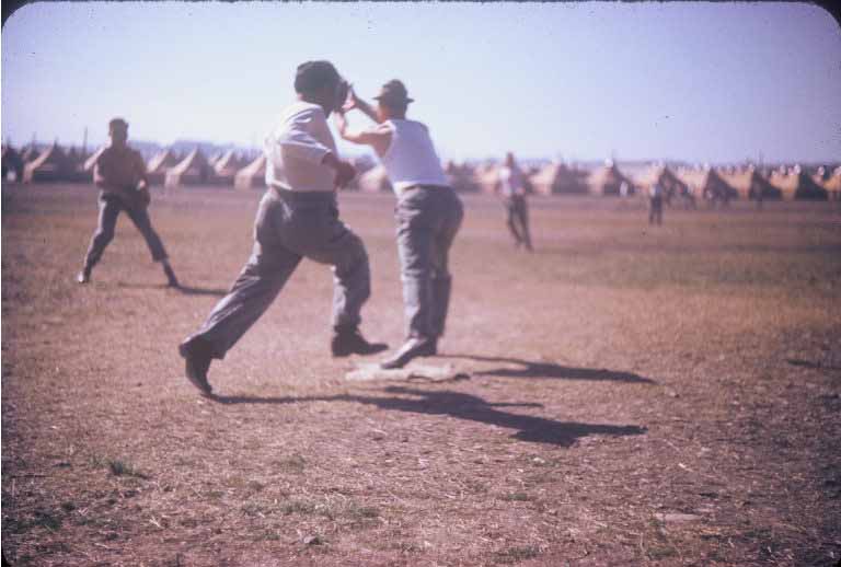 men playing baseball in the open field with people watching