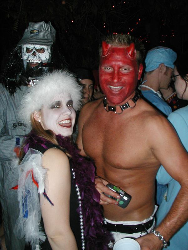 a man with red face paint on top of his head and a person in a devil costume