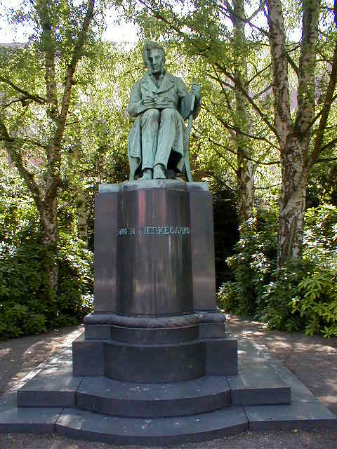 a statue of a man is sitting in front of trees
