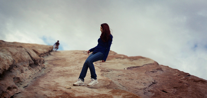 a woman is sitting on top of a large rock