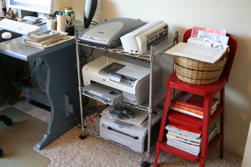 a room with a red chair a computer desk and a printer