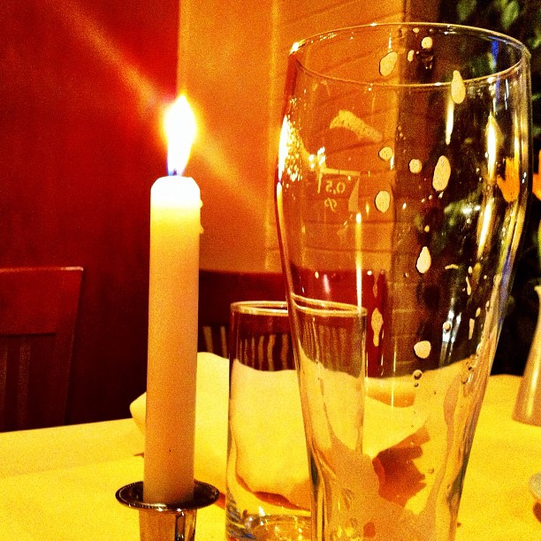 a table with a lit candle and empty glasses