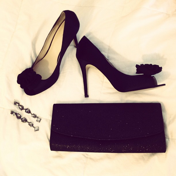 two black shoes and two purses laying on white sheet