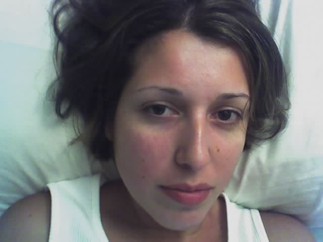 a woman with black hair laying down in bed