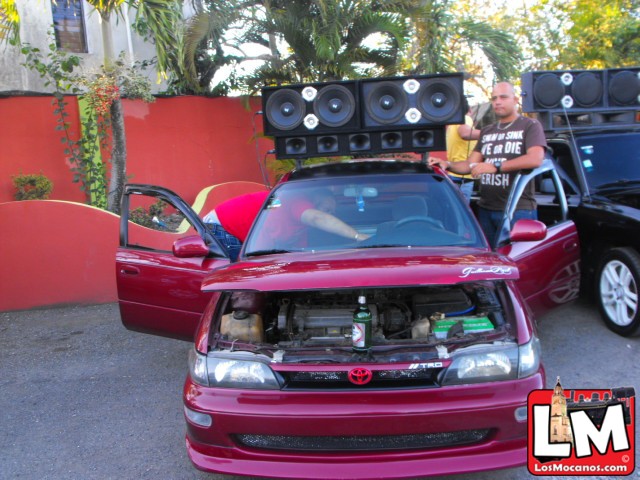 a man standing next to a car with speakers on the hood