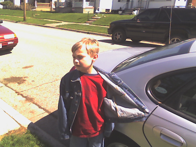 a child stands on a curb in front of parked cars