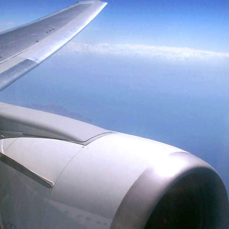 the wing of a plane flying high above the ground