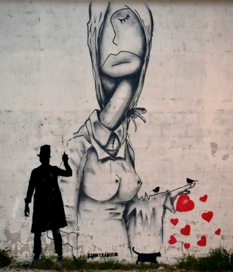 a person stands next to a graffitti on the side of a building