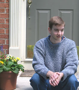 young man in blue sweater sitting next to door