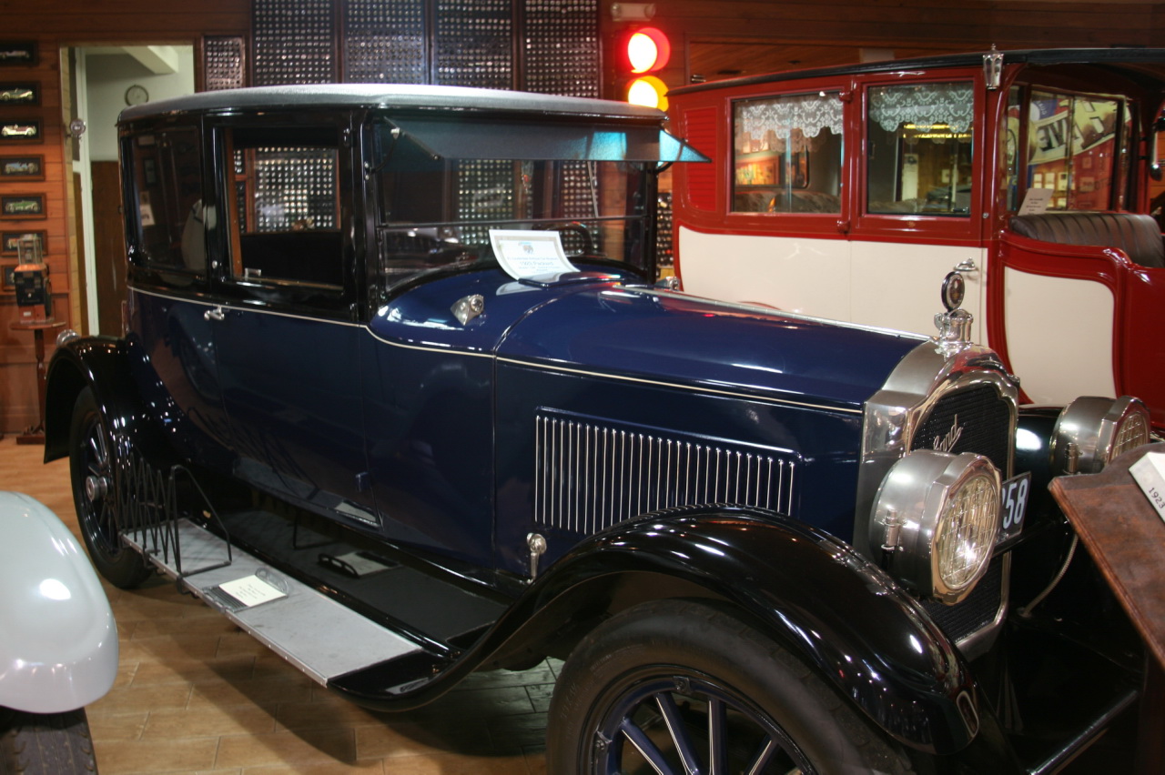 a blue antique car parked next to other vintage cars