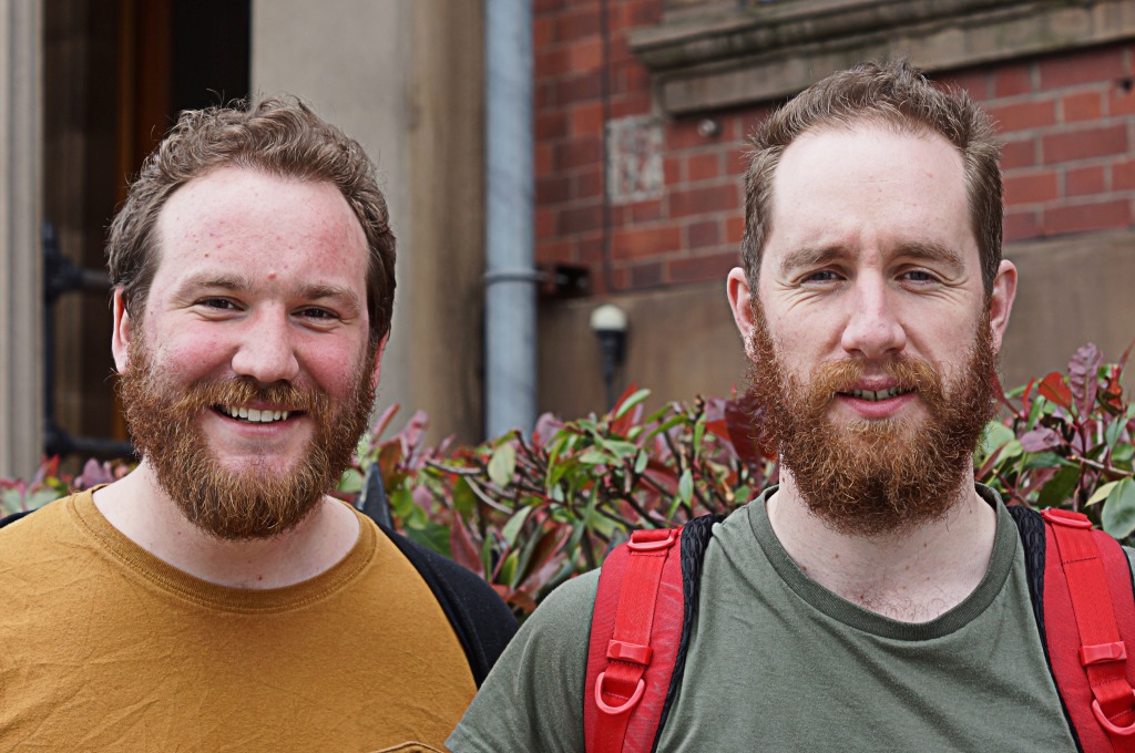 two bearded men with backpacks on are smiling
