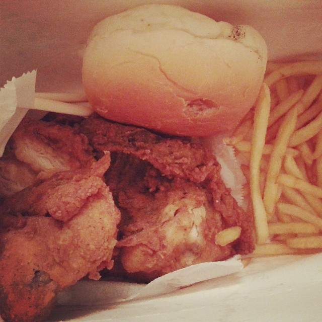 a basket containing chicken and french fries next to a roll