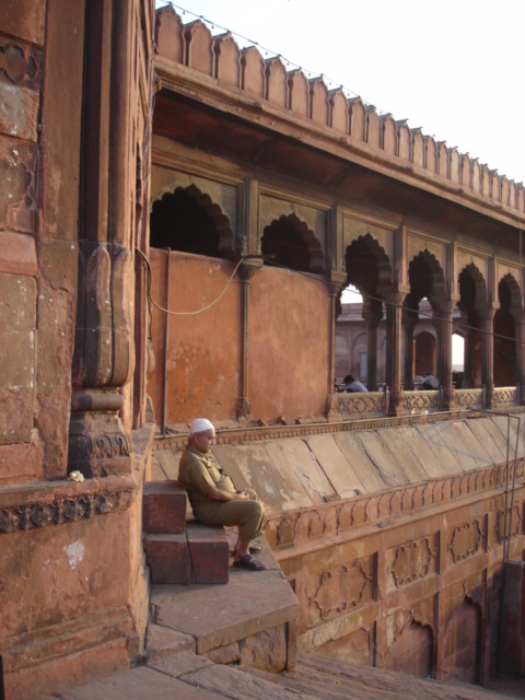 man sitting on a bench in front of an old building