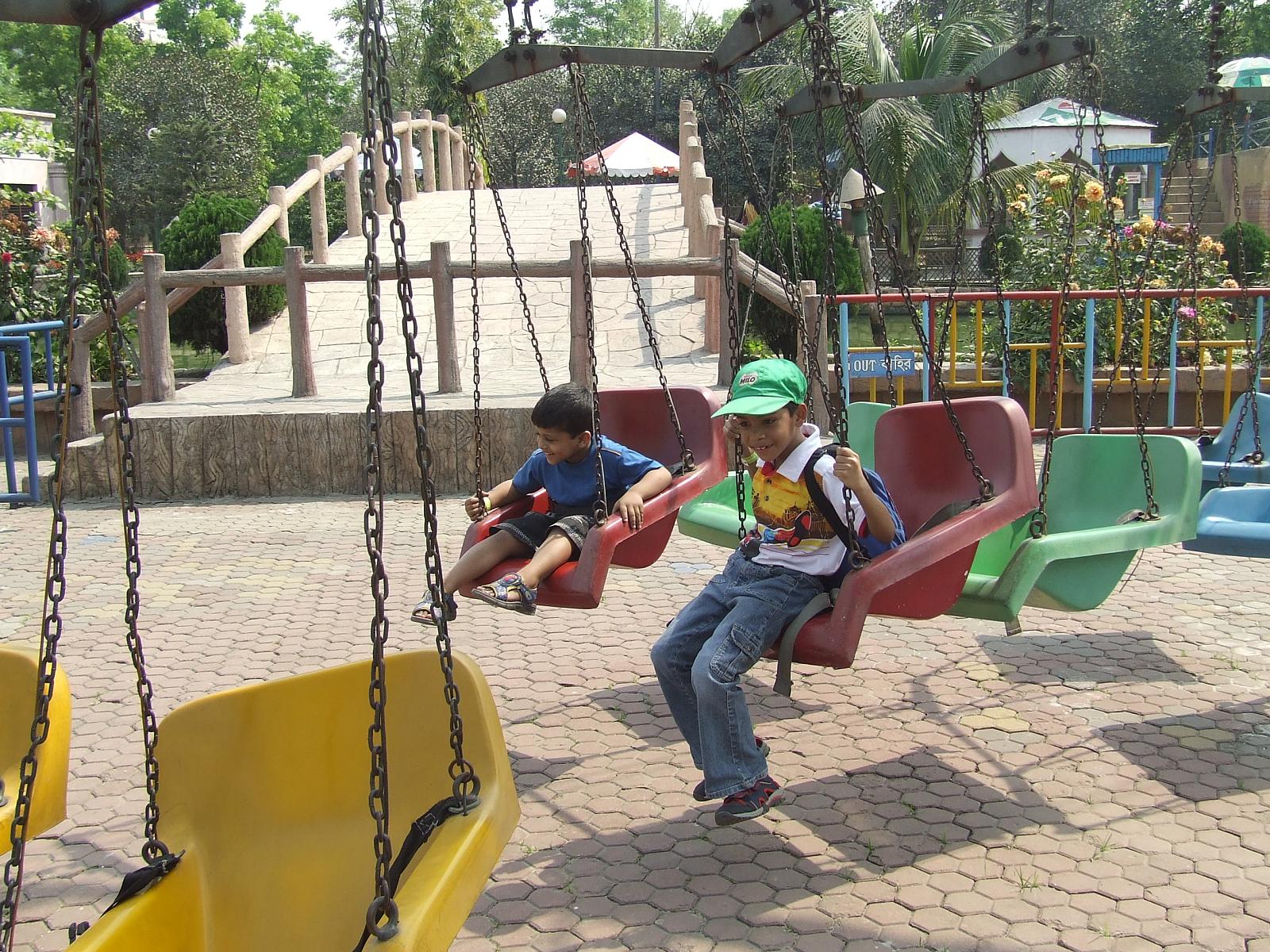 two s sitting on the swings at a playground