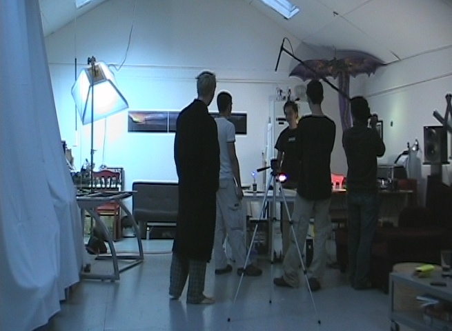 four men in a po studio talking with one man standing up