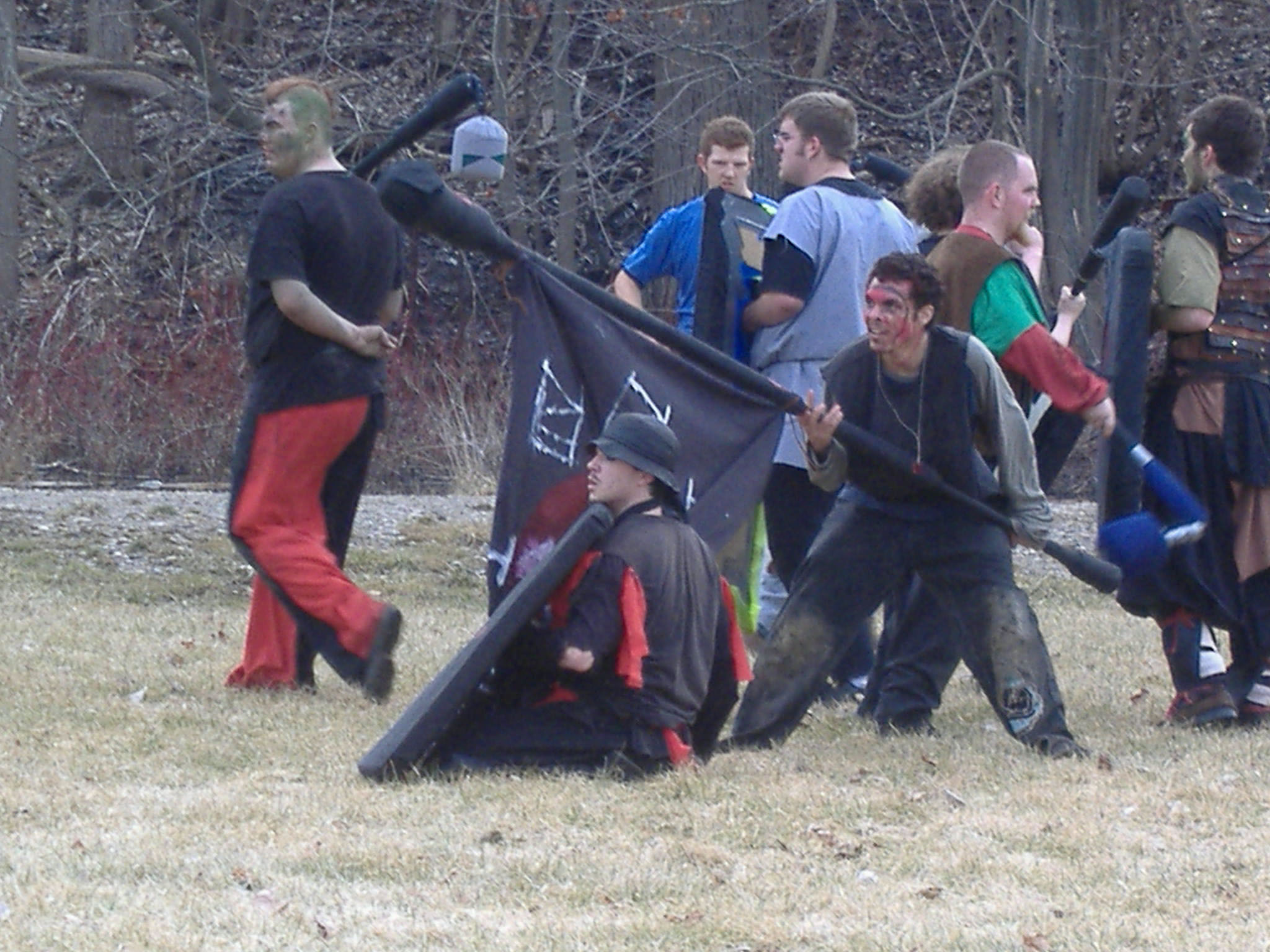 men walking out in the woods, with flags and baseball bats in hand