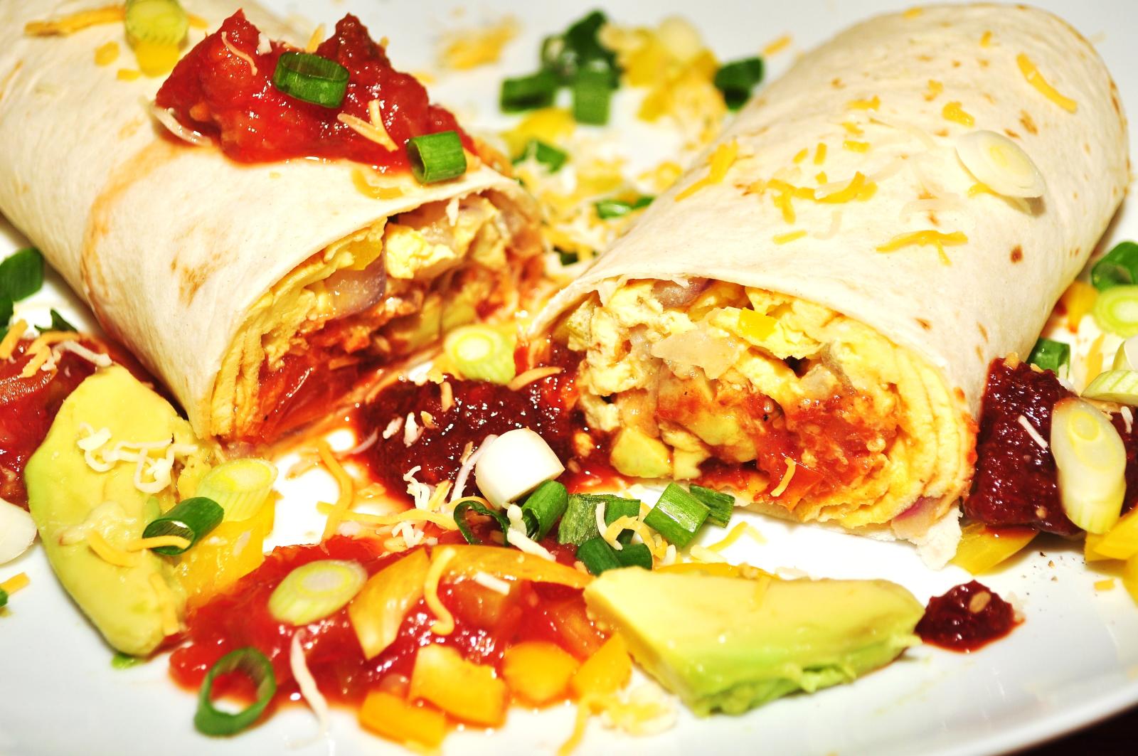 a plate topped with two burritos and fruit