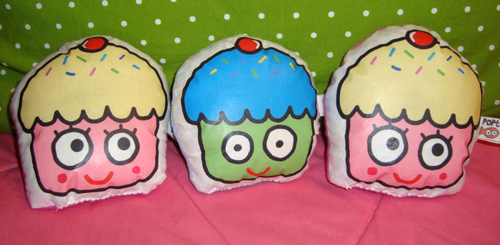 three pillows of different colored cakes on a pink surface