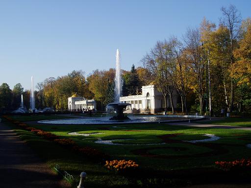 a park area with a fountain and several houses in the background