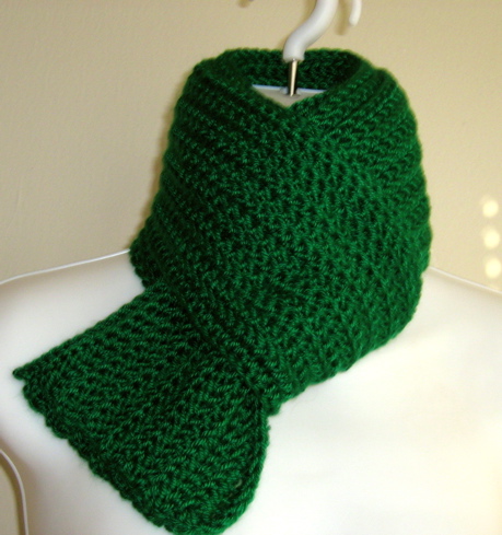 a green knit scarf hanging from a wall