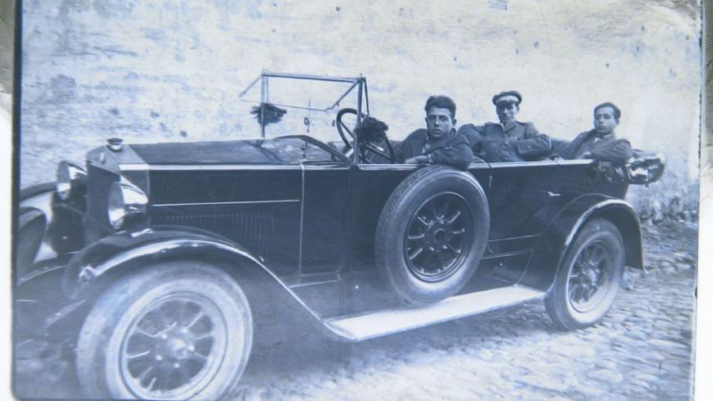 a picture of men with hats sitting in an old car