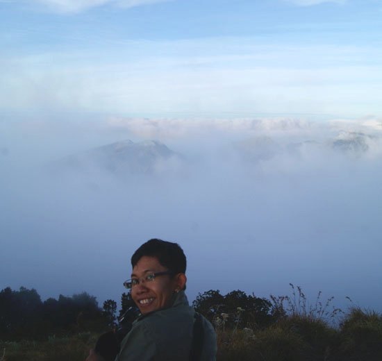 a man smiles while posing for the camera in front of a view of the clouds