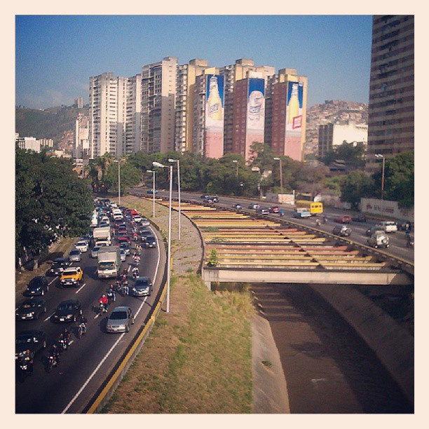 busy traffic on a city freeway with buildings and water behind it