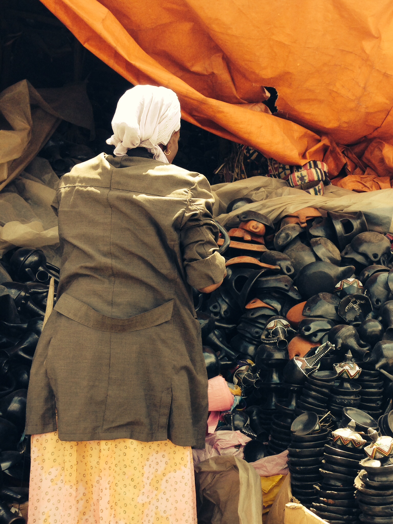 a woman walking past many large stacks of shoes