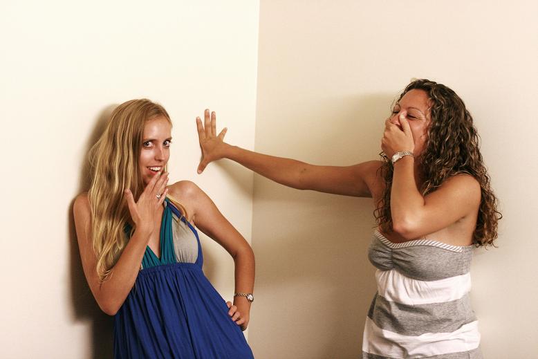 two girls standing next to each other and touching their mouths