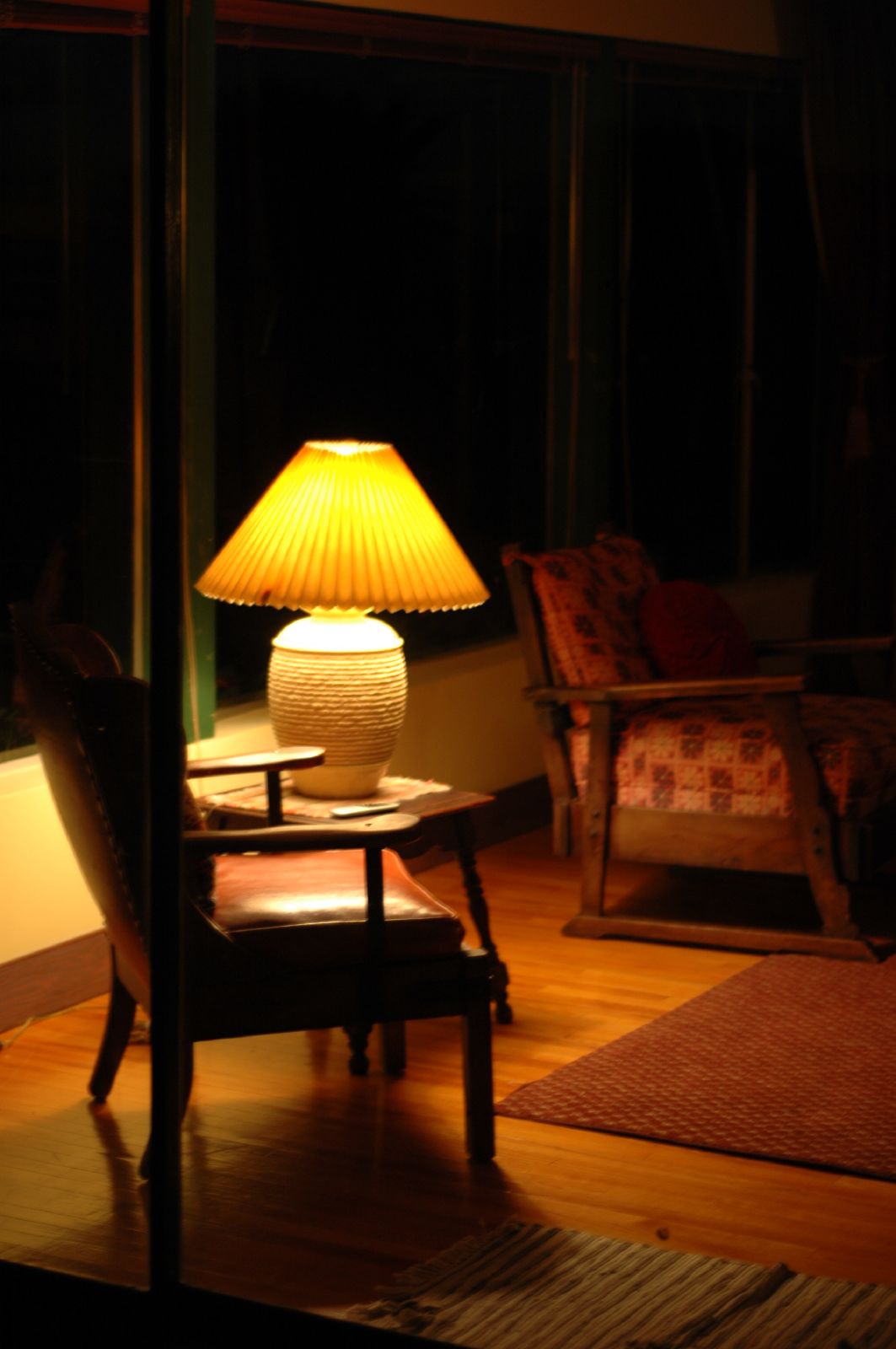 an empty chair sits on a wooden floor next to a lamp in a darkened room