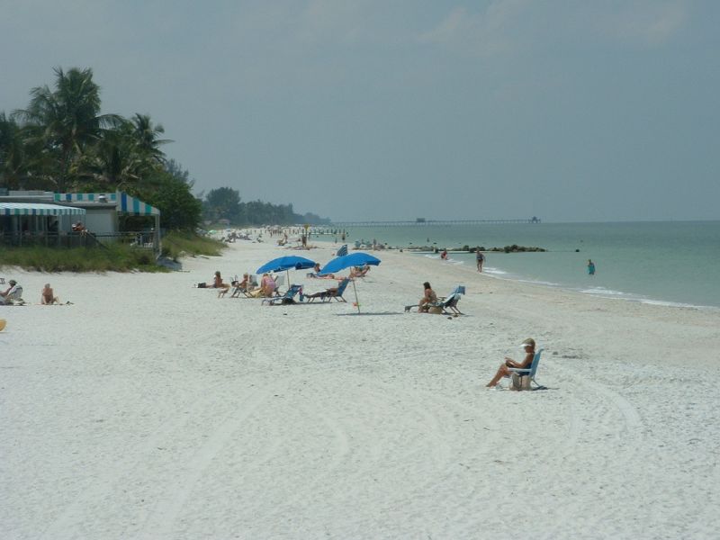 many people are on the sand near a large body of water