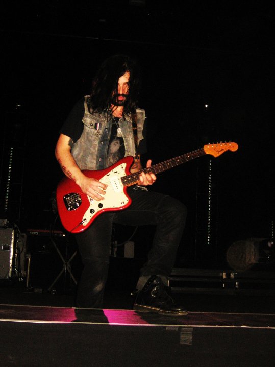 a man playing a red guitar on a stage