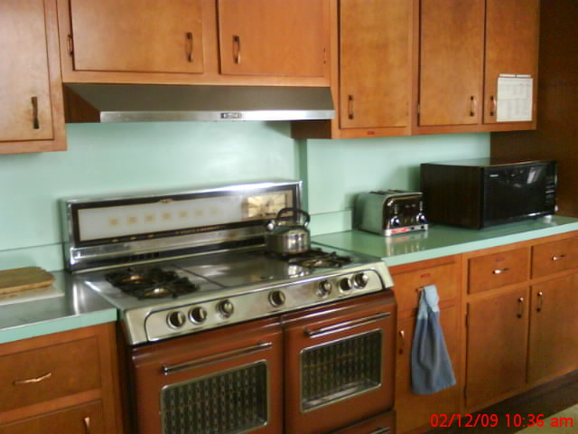 a kitchen with a stove and microwave with light blue walls