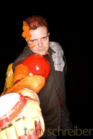 a man with painted eyes standing next to a plastic pumpkin