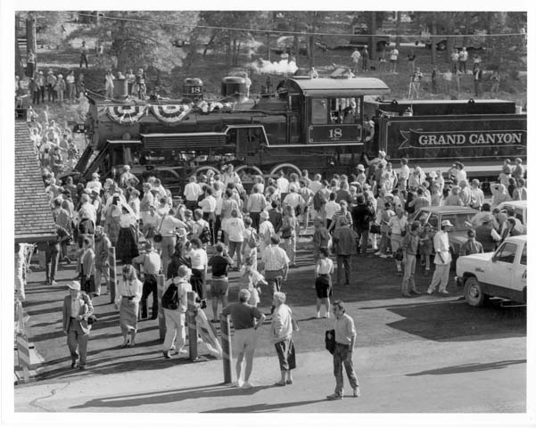 an old train traveling through a city surrounded by people