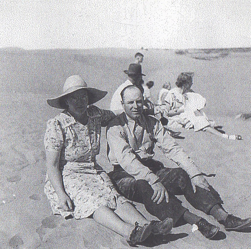 three men and a woman are sitting on the sand