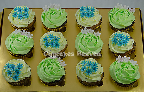 a bunch of green and blue cupcakes sitting on top of a cake