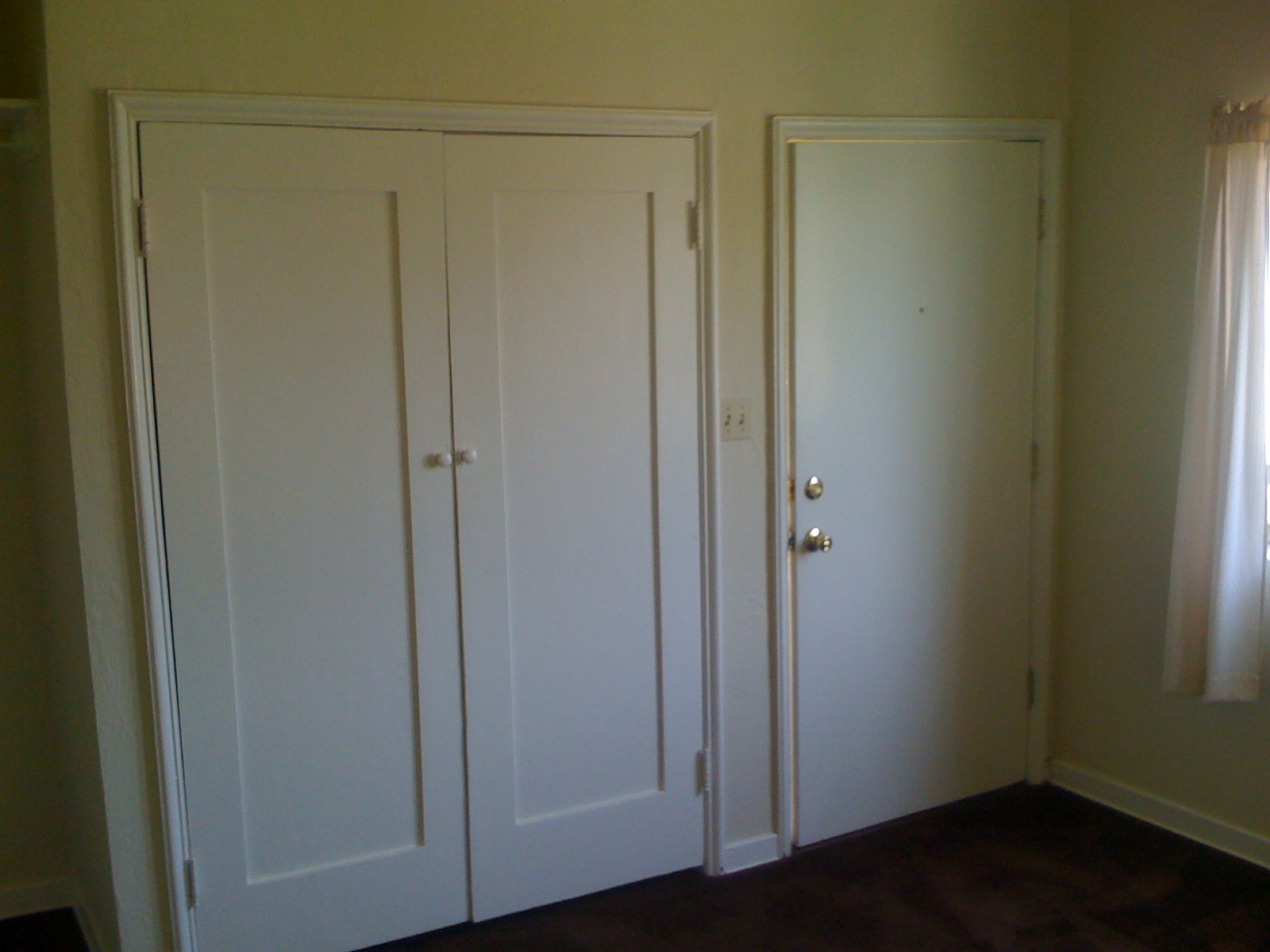 two white doors with s are in a corner of a room