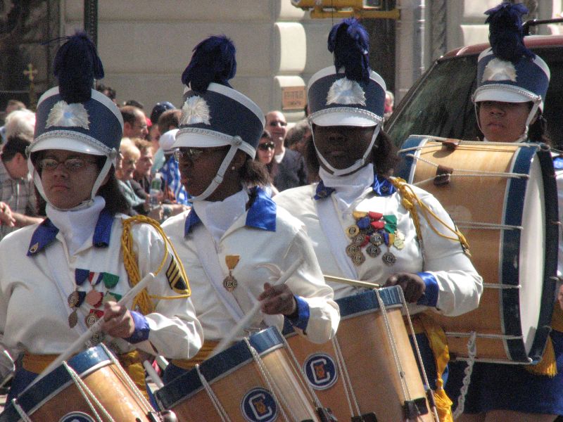 a large group of men in white outfits holding wooden drums and wearing hats