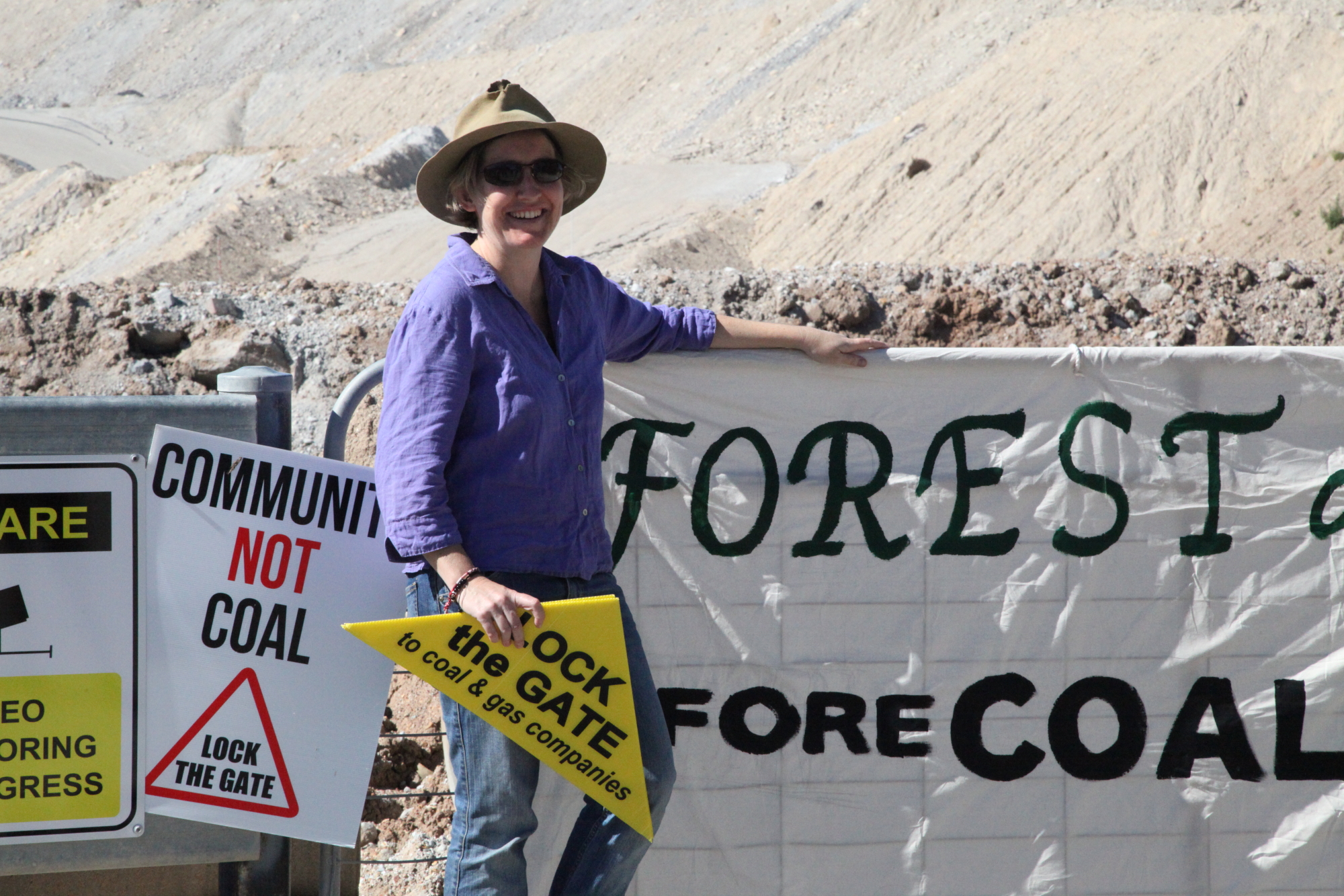 a woman stands by the sign as others hold up their signs