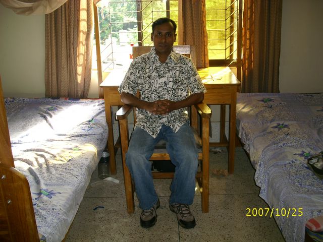 a man sits in a chair beside a bed