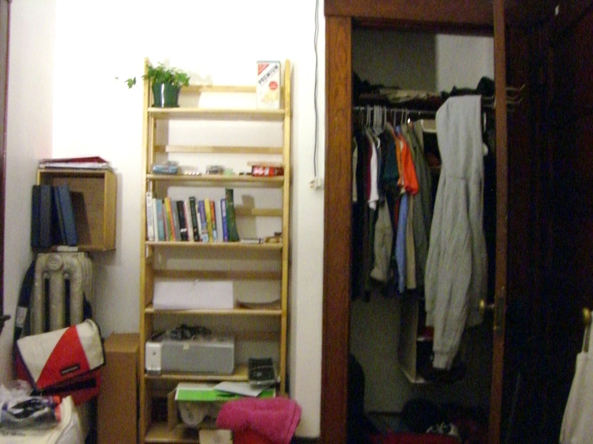 a messy bedroom with clothes hanging from the closet